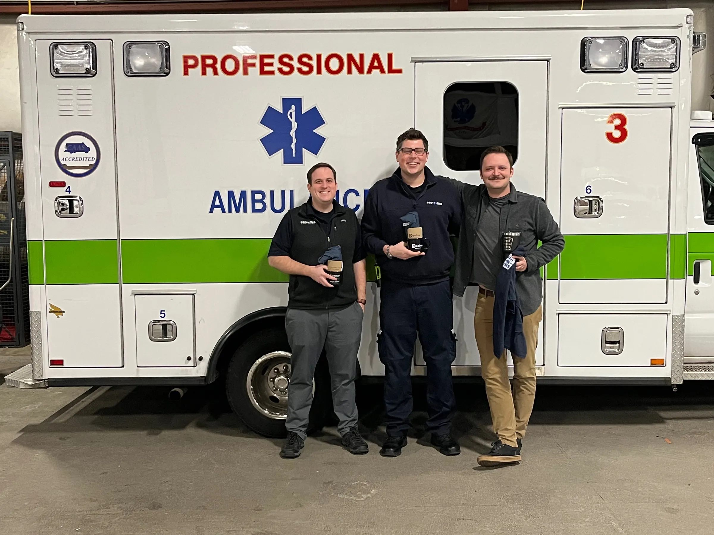 Pipeline with two crew members at a customer agency, standing in front of an ambulance in the bay.